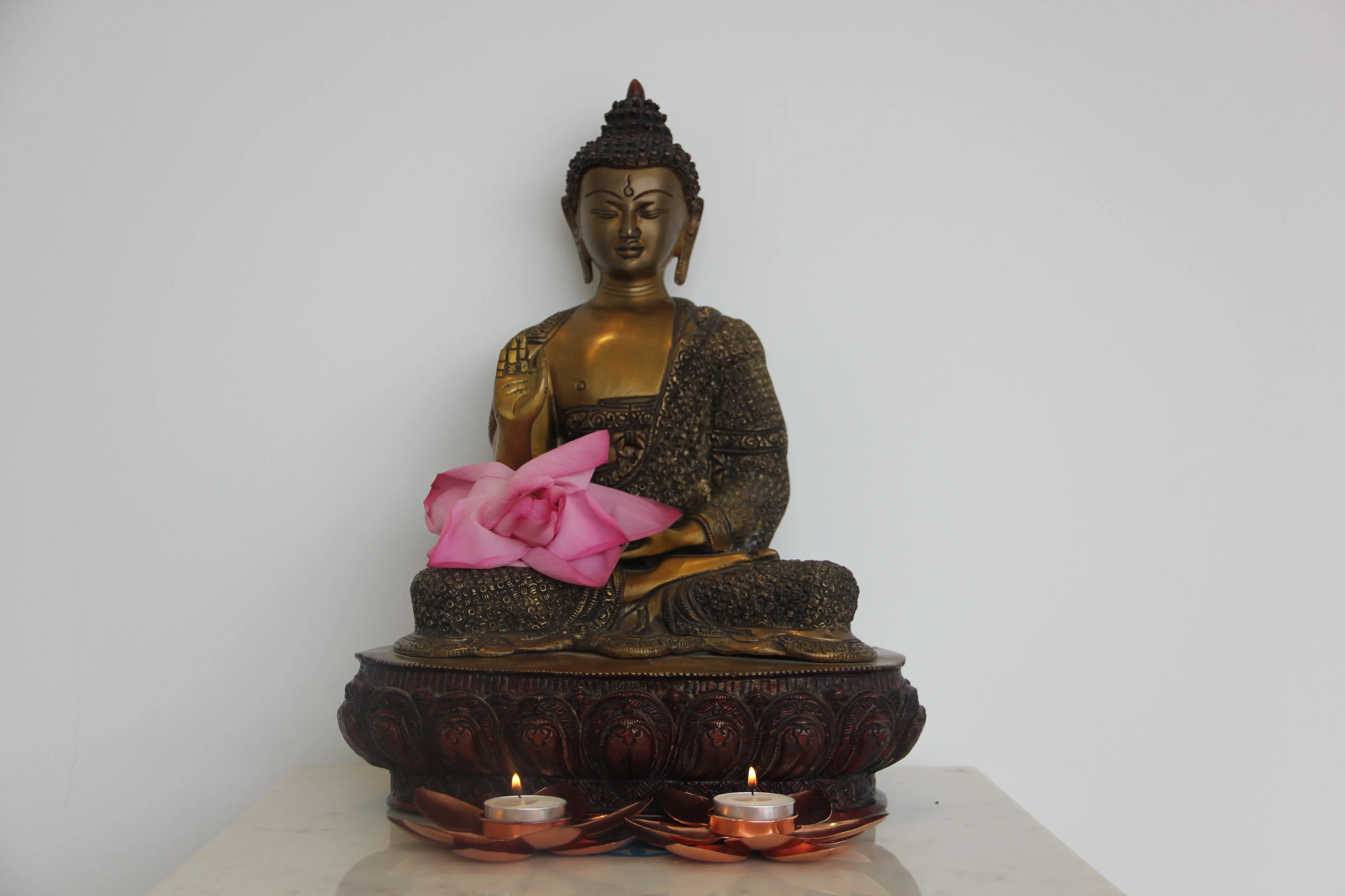 Buddha sculpture with a pink lotus and two candle lights inside the Prana center